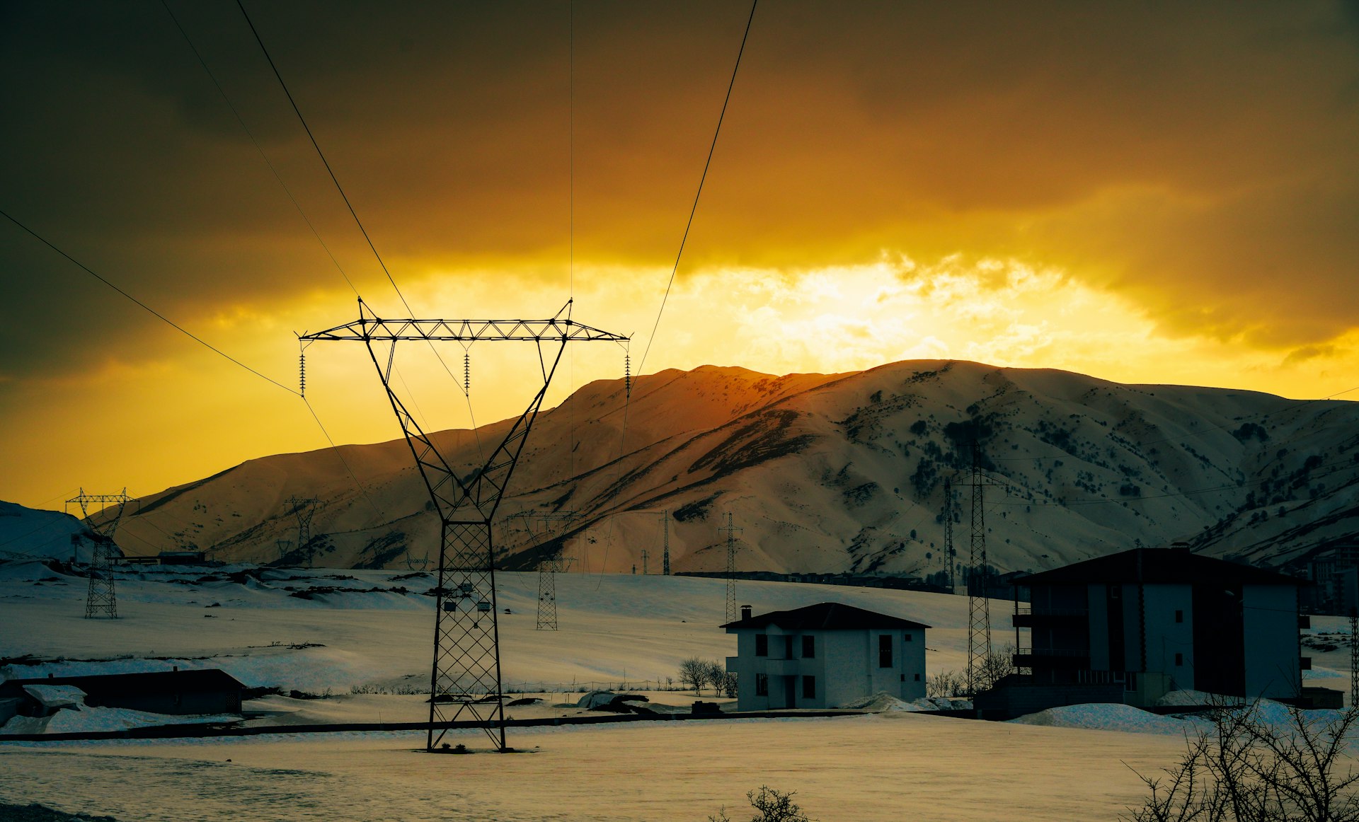 Transmission lines crossing a snowy landscape at dusk